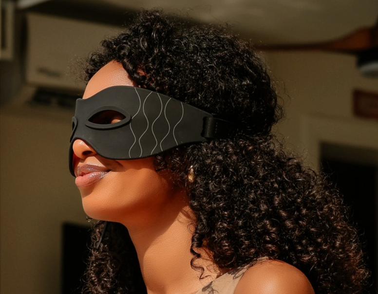 Woman wearing a SoulSkin red light LED eye mask while sitting by a pool.